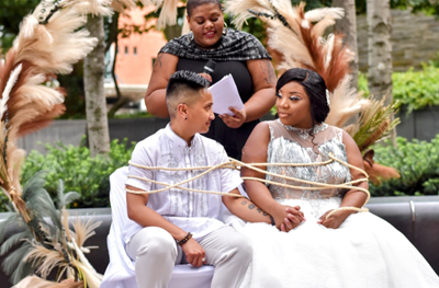 Mick Masaba and Jennifer Anderson sit next to each other at their outdoor wedding ceremony.